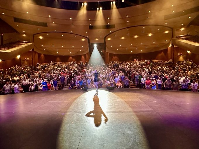 Jen Kramer taking a bow to a standing ovation in a packed performing arts theater